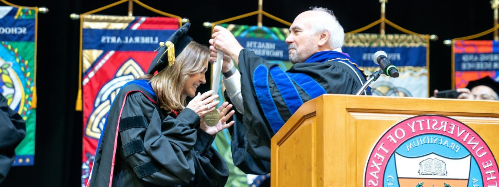 Dr. Arney receiving medal from Dr. Bailey on stage.